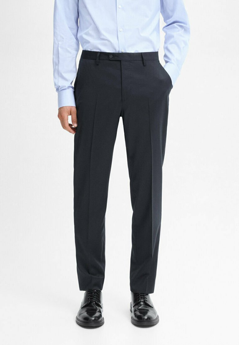 Pantalons de costume bleu marine foncé avec une coupe droite, devant plissé et passants de ceinture, associés à des chaussures noires brillantes et une chemise bleu clair.
