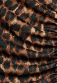 Tissu à imprimé léopard marron et noir avec des plis doux et une apparence texturée.