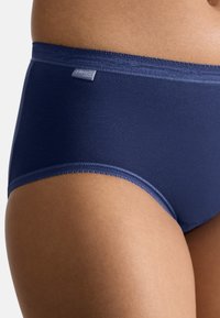 Braguitas de cintura alta en azul marino hechas de tela suave, con una cinturilla lisa, costuras delicadas y un sutil detalle de etiqueta de marca.