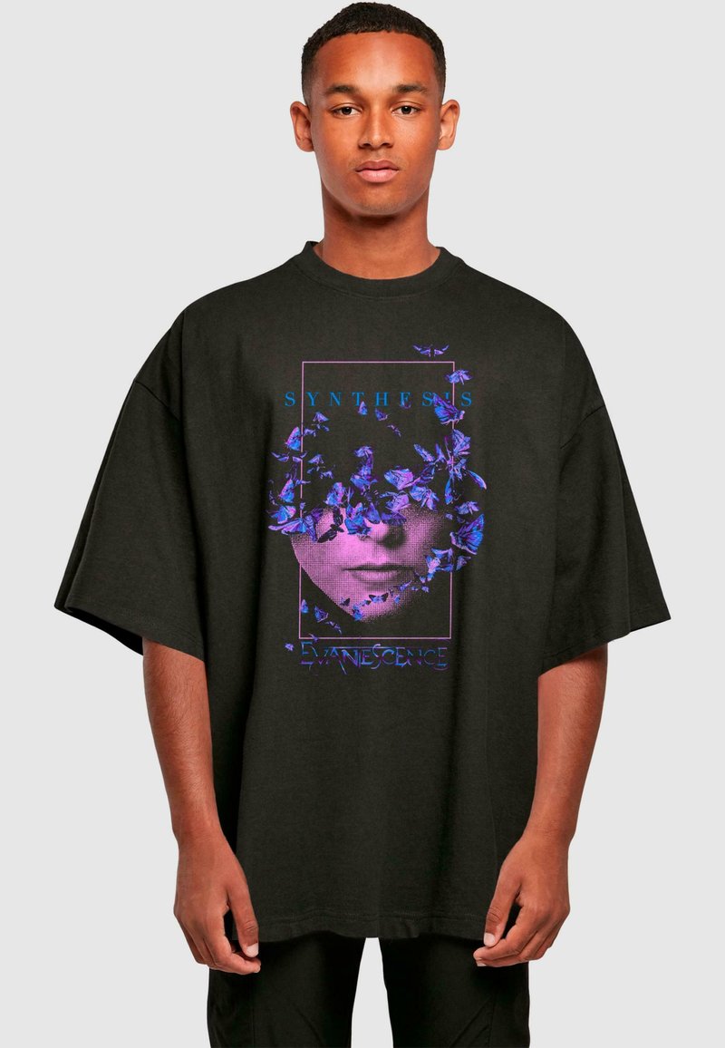 Sort oversized t-shirt med et grafisk design med lilla blomster og en ansigtssilhuet. Teksten lyder "SYNTHESIS" og "EVANESCENCE."
