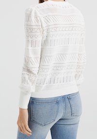 White knitted sweater featuring textured patterns and openwork details. Long sleeves with ribbed cuffs, round neckline, and fitted design.