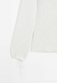 Biały dziany sweter z długim rękawem ze ściągaczem na mankiecie, na jednolitym białym tle.