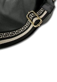 Zwarte leren schoudertas met een brede zwart-beige gestreepte band, voorzien van een gesp in goudkleur en een gestructureerd oppervlak.