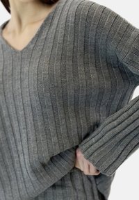 Maglione grigio a maglia con scollo a V, motivo a costine testurizzato e maniche lunghe con vestibilità rilassata. Materiale morbido e leggero.