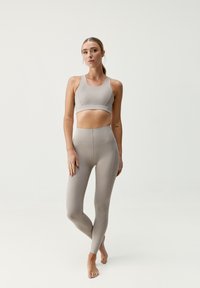 Ensemble de brassière de sport et de leggings beige clair, fabriqué en matériau extensible, avec un design sans couture et une taille haute. Texture lisse, sans motifs.