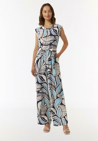 Wydrukowany kombinezon z granatowym tłem, z dużymi niebieskimi i beżowymi wzorami liści, krótkimi rękawami, paskiem do zawiązania i szerokimi nogawkami.
