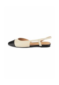 Scarpe slingback beige con punta nera, suola piatta e design laterale con ritaglio. Realizzate in pelle liscia con semplici dettagli di cucitura.