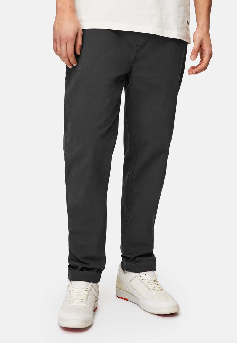 Dark gray chinos with a straight cut, featuring side pockets and a smooth texture, paired with white sneakers.