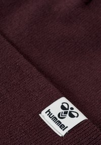 Burgundy strikket hat med tekstureret overflade og et hvidt mærke med "hummel" logoet og et grafisk ikon.