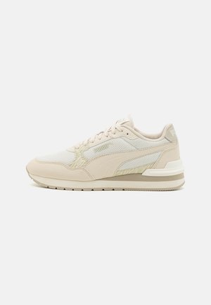 Light beige sneaker with mesh and leather materials, featuring a textured design, cushioned sole, and subtle logo accents.