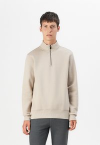 Light beige zip-up sweatshirt with a high collar, ribbed cuffs, and hem. Soft texture, relaxed fit, minimalistic design.