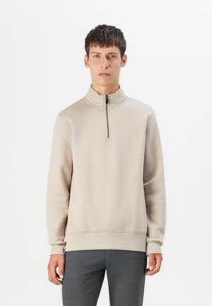 Light beige zip-up sweatshirt with a high collar, ribbed cuffs, and hem. Soft texture, relaxed fit, minimalistic design.