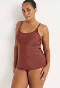 Brun badetop med tynde stropper, samlet frontdesign og en løs, svævende pasform. Parret med en matchende brun bikiniunderdel.