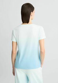 T-shirt léger à manches courtes dégradé allant du blanc au bleu clair, avec un col rond et une texture lisse.