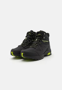 Black hiking boots with green accents, synthetic upper, padded collar, rubber sole, and textured lace design for secure fit.