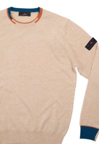 Beige trui met ronde hals gemaakt van zachte stof, met blauwe en oranje accenten bij de kraag en manchetten, en een logopatch op de mouw.