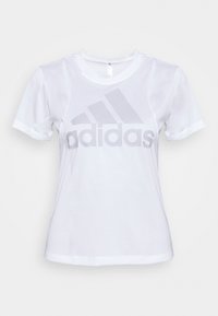 Camiseta blanca de mangas cortas hecha de una tela suave que presenta un gran logo de Adidas en gris claro en el pecho. Diseño sencillo de cuello redondo.