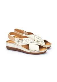 Weiße Leder-Sandalen mit komplexen Ausschnittmustern, braunen Akzenten und genähten Details auf der Sohle. Verstellbarer Riemen für eine optimale Passform.