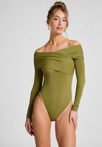 Olijfgroen longsleeve bodysuit met off-the-shoulder ontwerp, textuurstof en hoog uitgesneden benen. Slanke, aansluitende silhouet.