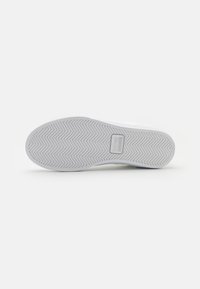 Hvit gummisole på sneakers med fiskebensmønster og rektangulært merke. Rent design, jevn tekstur, minimal detaljering.