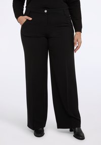 Czarne spodnie szerokie w gładkim, elastycznym materiale. Posiadają dwie kieszenie z przodu oraz zapinanie na guzik z przodu.
