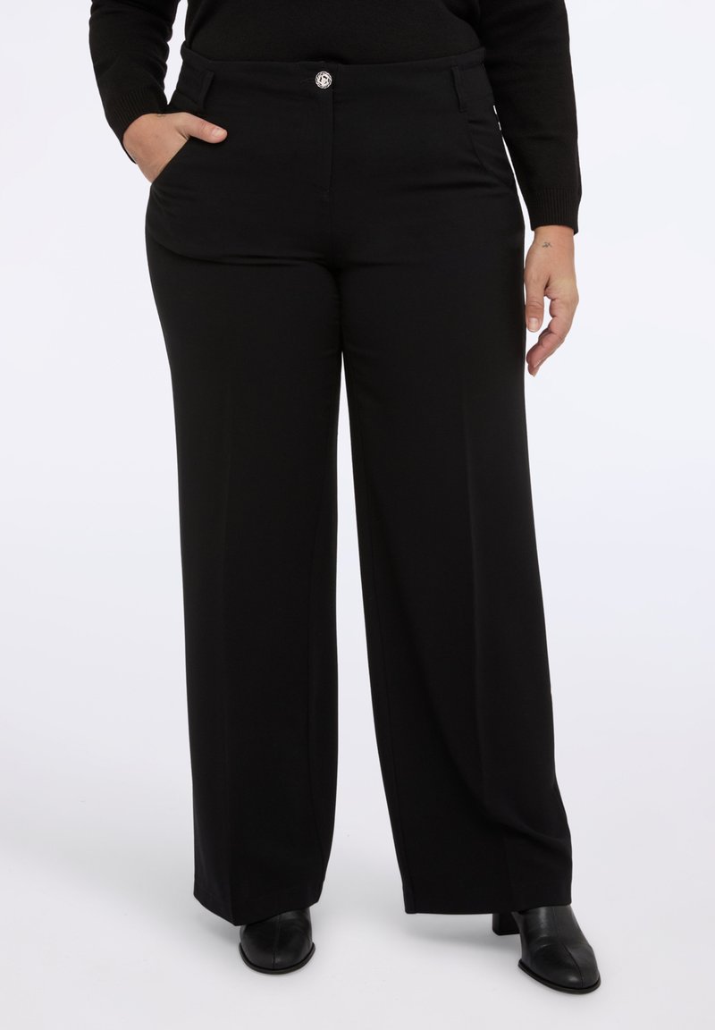 Czarne spodnie szerokie w gładkim, elastycznym materiale. Posiadają dwie kieszenie z przodu oraz zapinanie na guzik z przodu.