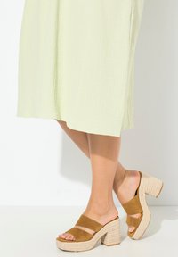 Bruna mockaskinnsplattformssandaler med två breda remmar, flätad jute-mellansula och en klumpig, strukturerad klack. Slät sula och öppen tå-design.