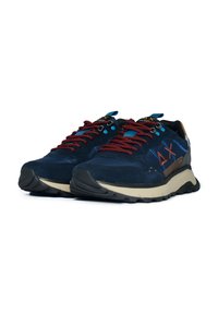 Sneaker in suede blu navy con lacci a motivo rosso, dettagli blu e suola intermedia color crema. Presenta un colletto imbottito e suola testurizzata.