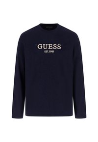 Maglietta a maniche lunghe blu marina realizzata in morbido tessuto, con la scritta "GUESS EST.1981" ricamata in beige sul petto, colletto a giro e design semplice.