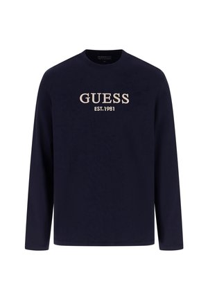 Navy long-sleeve shirt made of soft fabric featuring "GUESS EST.1981" in beige embroidery on the chest, with a crew neck and simple design.