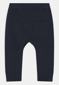 Navyblaue, weiche Baumwollleggings mit schmal zulaufendem Bein, elastischem Taillenbund und einer einzelnen Gesäßtasche. Glatte Textur mit gesteppten Details.