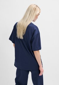 Mörkblå oversized T-shirt i mjuk bomull. Har korta ärmar och rund halsringning, med en avslappnad passform och slät textur.
