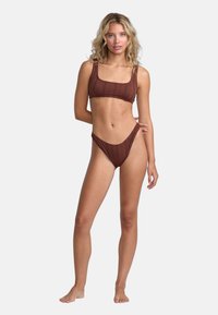 Brun bikiniuppsättning med en texturerad ribbad design, fyrkantig halsringning på toppen och högskurna byxor med minimalt skydd.