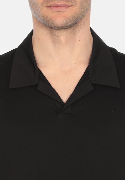 Polo nero con colletto, maniche corte e una sottile texture opaca. Presenta una patta parziale e un design a vestibilità rilassata.