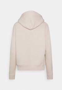 Světle béžová mikina s kulatou kapucí, spadlými rameny a žebrovanými manžetami. Vyrobena z měkké látky s čistým, minimalistickým designem.