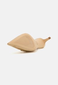 Scarpa beige a punta con un design elegante, texture liscia e tacco basso; presenta una suola leggermente stampata per una presa migliore.