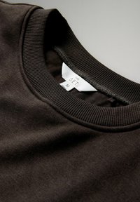 Czarny sweatshirt z prążkowanym okrągłym dekoltem, miękka tekstura, widoczna metka z napisem "THE SET" i rozmiarem "M". Brak ozdób lub wzorów.