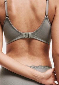 Šedá bavlněná podprsenka s hladkým povrchem, tenkými nastavovacími ramínky a zapínáním na háček a oko na zadní straně. Krajkový lem podél pásu.