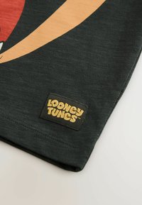 Černé bavlněné tričko s barevným grafickým motivem Looney Tunes a černou etiketou s textem "Looney Tunes" ve zlaté barvě. Měkká textura, standardní střih.