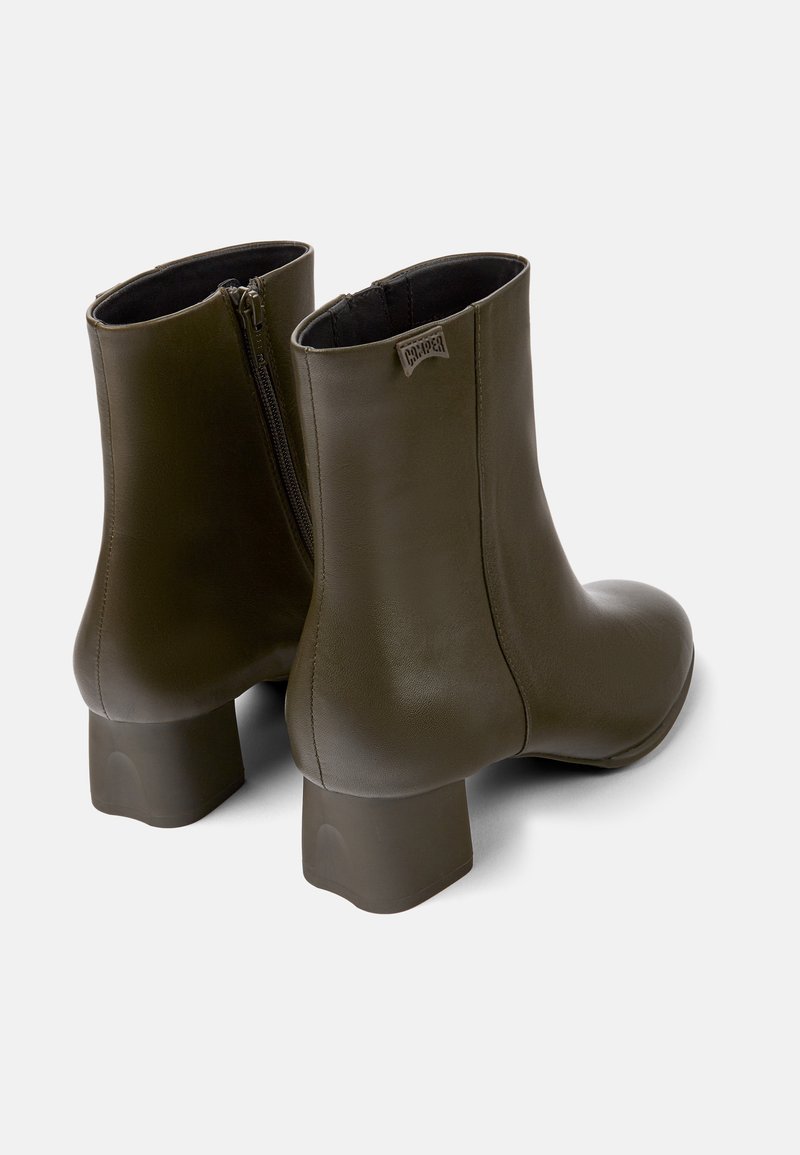 Bottes ankle vert olive avec une finition en cuir lisse, des talons carrés et une fermeture éclair sur le côté pour un enfilage facile. Texture lisse, design minimaliste.