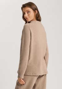 Beiger, strukturierten Pullover mit rundem Ausschnitt und langen Ärmeln. Hat einen lässigen Schnitt und ein weiches Material, Rückansicht zeigt Saum- und Ärmeldetails.