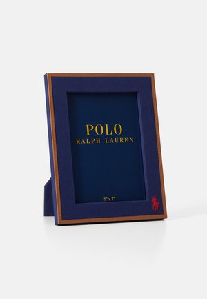 Okvir tamnoplave boje s teksturiranim završetkom, zlatnim natpisom i crvenim logom polotopa. Dizajniran za fotografiju veličine 5"x7", uključuje smeđu naglašenu ivicu.