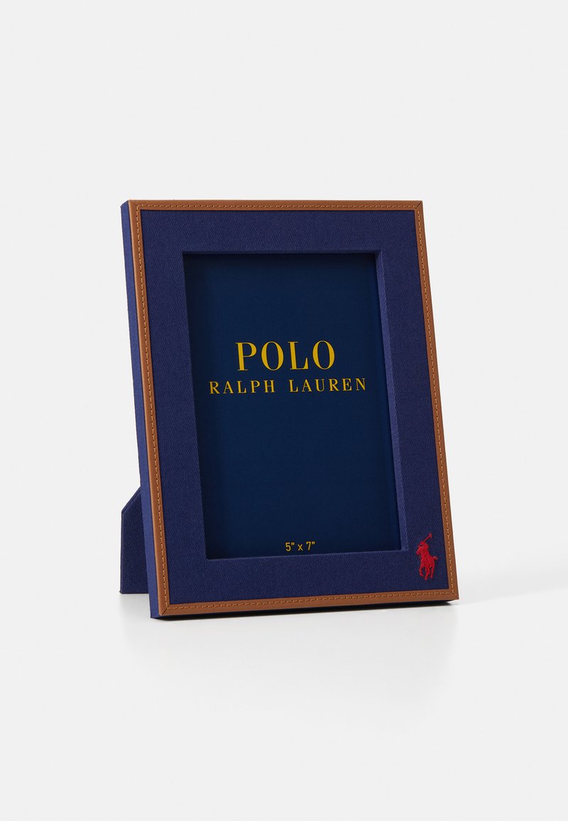 Tamsiai mėlynas rėmas su struktūrizuotu paviršiumi, auksinės spalvos užrašas ir raudonas polo logotipas. Sukurtas 5"x7" nuotraukai, turi rudą akcentinį kraštą.