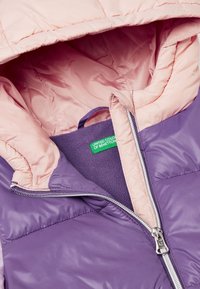 Fialová a růžová prošívaná bunda s dvojitým zipem, která má měkkou fleecovou podšívku a štítek s nápisem "United Colors of Benetton."
