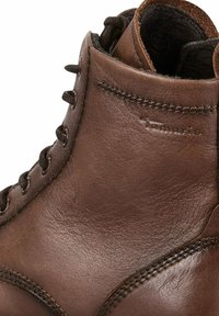 Stivale alla caviglia in pelle marrone con finitura testurizzata, forma arrotondata, occhielli in metallo e lacci, con dettagli di cucitura e logo del marchio.