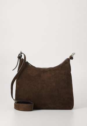 Sac à bandoulière en daim marron foncé avec sangle réglable et fermeture éclair argentée, présenté sur un fond gris clair.