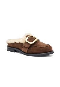 Chaussure slip-on en daim marron avec doublure en fausse fourrure et un détail de boucle dorée proéminent. La semelle plate est noire avec un bord texturé.