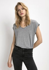 Grå crew-neck t-skjorte med rullede ermer, laget av mykt, lett materiale. Kombinert med høyt liv svarte jeans.