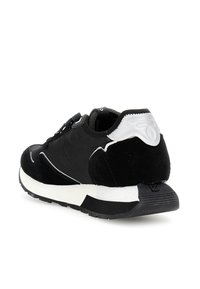 Sneaker atletico bianco e nero angolato per mostrare il retro e il lato, caratterizzato da materiali in suede e mesh con una suola testurizzata.