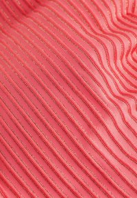 Lyserødt stof med bølgede, strukturerede lodrette striber og tynde, skinnende metalliske tråde vævet igennem.